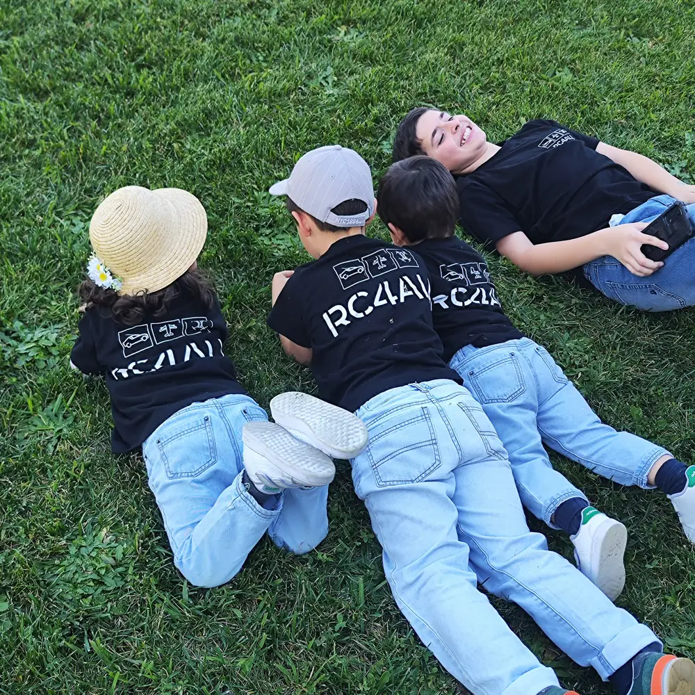 Quatro jovens deitados na relva com as t-shirts da RC4All, entre voltas com os modelos