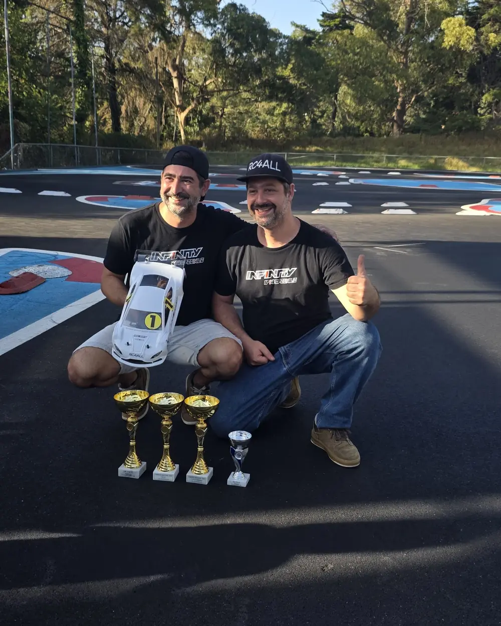 Os dois irmãos fundadores da RC4All na pista, com os troféus e um modelo à escala